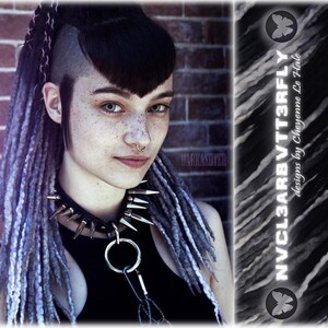 May include: A black choker featuring silver-toned metal spikes and a central O-ring with a carabiner attachment. The accessory is worn with long, textured grey and black synthetic dreadlocks and a septum piercing, with text reading NVCL3ARBVT3RFLY.
