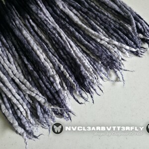 May include: A collection of long, thin, twisted synthetic hair extensions featuring a gradient color transition from deep black at the top to a light grey and white at the ends. The text NVCL3ARBVTT3RFLY designs by Cheyenne Le Hale is visible.