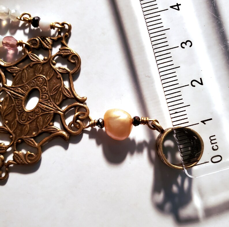 May include: A gold-toned pendant necklace with a filigree design and a pearl bead. The necklace is 1 cm long.
