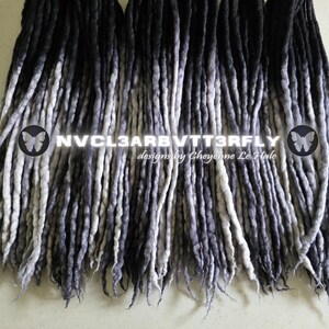 May include: A collection of synthetic dreadlocks featuring a gradient color transition from black at the roots to light gray at the tips. The text NVCL3ARBVTT3RFLY and designs by Cheyenne Le Hale are overlaid on the center of the dreadlocks.