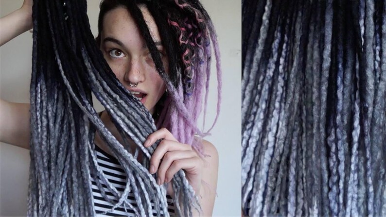 May include: A set of synthetic dreadlocks featuring a color gradient that transitions from deep black at the roots to a light grey at the tips. The texture is twisted and rope-like, with some strands showing a mix of black, grey, and light purple.
