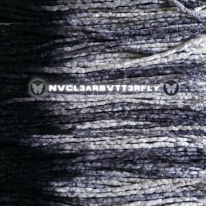 May include: A collection of long, thin, braided hair extensions featuring a gradient color pattern that transitions from deep black to charcoal gray and bright white. The text NVCL3ARBVTT3RFLY designs by Chyenne Le Hale is centered.