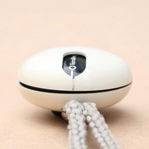 May include: White round device with a black label that says "O Termalit" hanging from a white cord.
