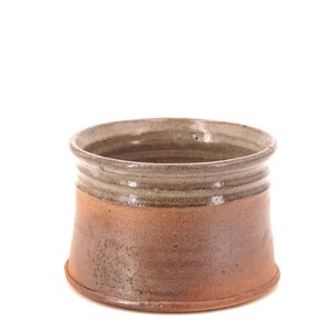 May include: A brown and grey ceramic bowl with a rounded bottom and a slightly flared rim.