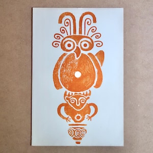 May include: Orange print on a light blue background. The print features a stylized owl figure atop a human-like figure, with a vase at the bottom. The owl has large eyes and decorative head feathers. The figures are in a stacked arrangement.