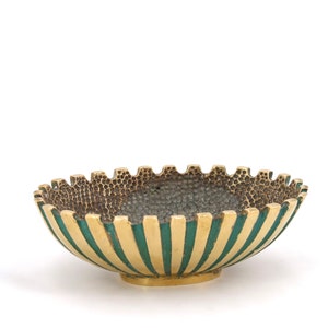 May include: A small, gold-colored bowl with a green striped pattern around the rim. The bowl has a textured, hammered surface.
