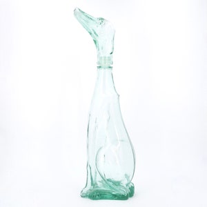 Peut inclure: Une bouteille en verre transparent en forme de chien, avec la t&ecirc;te du chien formant le bouchon. La bouteille est de couleur vert clair et pr&eacute;sente un design lisse et incurv&eacute;. Le chien est assis.