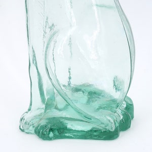 Peut inclure: Une figurine de chat en verre transparent vert clair. Le chat est assis, avec ses pattes avant visibles. Le verre a une surface l&eacute;g&egrave;rement textur&eacute;e. La figurine est sur fond blanc.