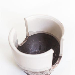 May include: White ceramic yarn bowl with a black speckled interior and three openings for yarn.