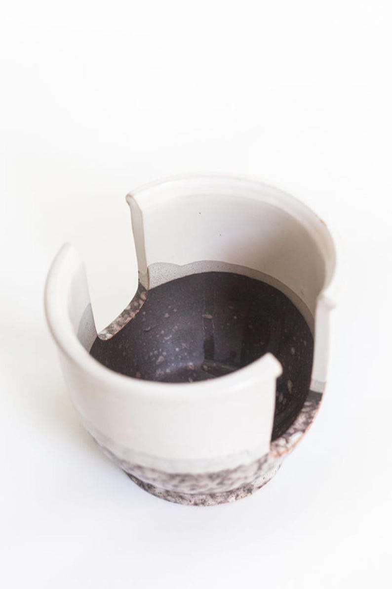 May include: White ceramic yarn bowl with a black speckled interior and three openings for yarn.