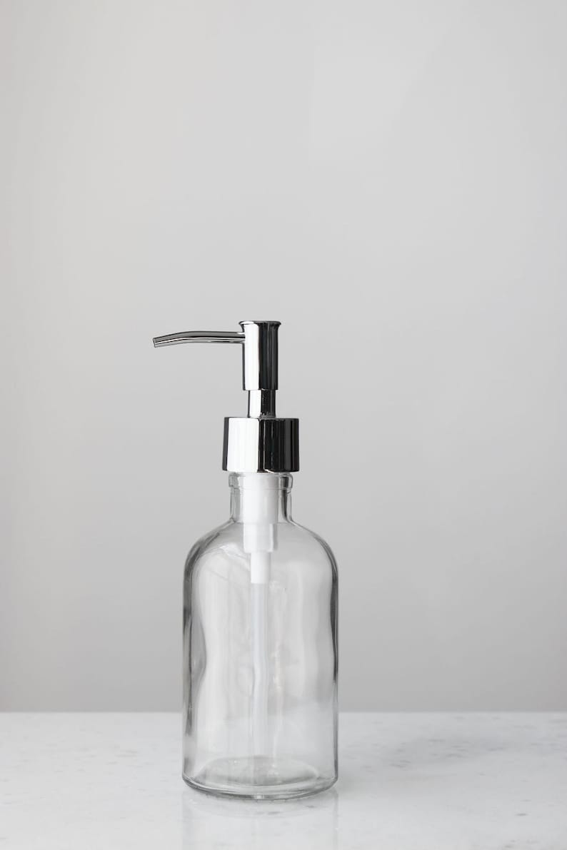 May include: A clear glass bottle with a chrome pump dispenser. The bottle is empty and ready to be filled with soap or lotion.