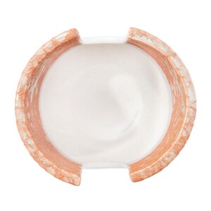 May include: A white ceramic dish with a terracotta rim. The dish has a unique shape with two cutouts on the sides.
