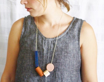 May include: A woman wearing a gray sleeveless top with a necklace made of wooden beads in blue, brown, and pink.