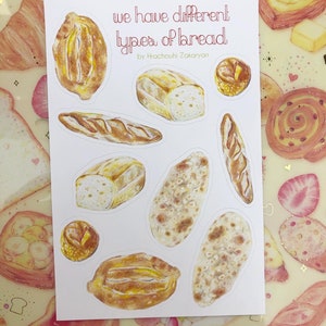 May include: A white card with the text "we have different types of bread" and the name "Hrachouhi Zakaryan" printed on it. The card features illustrations of various types of bread, including a baguette, a loaf of sourdough, and a round loaf of bread.