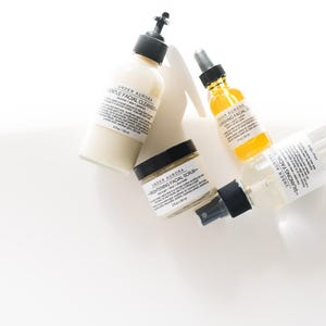 K&ouml;nnte beinhalten: Draufsicht auf vier Hautpflegeprodukte von "Under Aurora" auf wei&szlig;em Untergrund. Die Produkte umfassen einen sanften Gesichtsreiniger, ein kl&auml;rendes Gesichts&ouml;l, ein aufhellendes Gesichtspeeling und einen ausgleichenden Gesichtsspray.