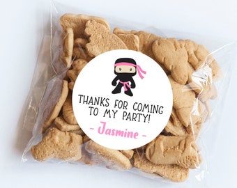 May include: A white circle sticker with a black and pink ninja cartoon character. The sticker says "Thanks for coming to my party! - Jasmine -"