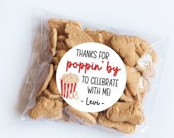 May include: White circle favor tag with red text that says "Thanks for poppin' by to celebrate with me! - Levi -" and a red and white illustration of a popcorn bucket.