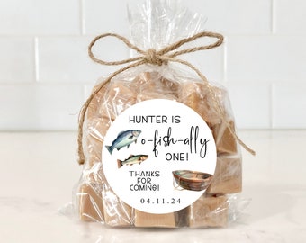 May include: A clear cellophane bag tied with twine, filled with caramel-colored candies. A round sticker on the bag reads "Hunter is o-fish-ally one!" with fish illustrations and the date 04.11.24. The words "Thanks for coming!" are also included.