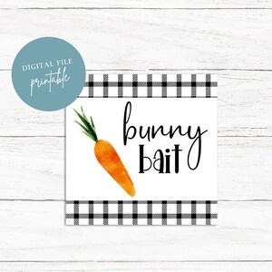 May include: Printable sign with a black and white checkered border. The sign has a white background with a watercolor carrot and the text "bunny bait" in black.
