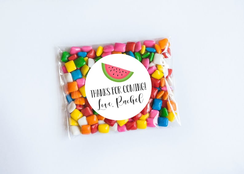 May include: A white circle sticker with a watermelon graphic and the text "Thanks for coming! Love, Rachel". The sticker is on a clear plastic bag filled with colorful candy.