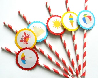 May include: Six red and white striped paper straws with colorful paper circles attached. The circles feature beach-themed images, including a crab, a sandcastle, a sun, an ice cream cone, a beach ball, and an umbrella.