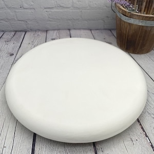May include: A white round cake stand with a smooth, slightly rounded surface. The stand is made of a sturdy material and is perfect for displaying cakes, cupcakes, or other desserts.