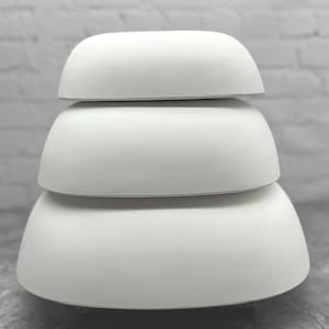 May include: Three white ceramic bowls stacked on top of each other. The bowls are round and have a smooth, glossy finish.