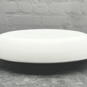 May include: A white ceramic round plate with a slightly raised edge. The plate is smooth and has a matte finish.