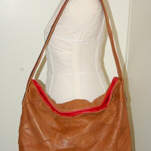 May include: A brown leather patchwork tote bag with a red lining and a long brown strap.