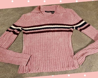 May include: A pink long-sleeved sweater with a ribbed texture and a white, black, and burgundy striped pattern. The sweater has a collared neckline and the brand name "FOREVER 21" is visible on the collar.
