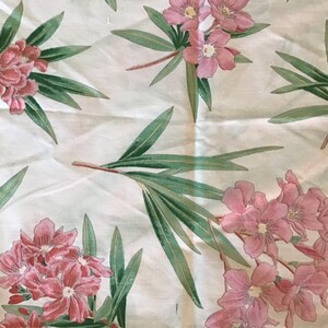 May include: White fabric with a floral pattern featuring pink flowers and green leaves.