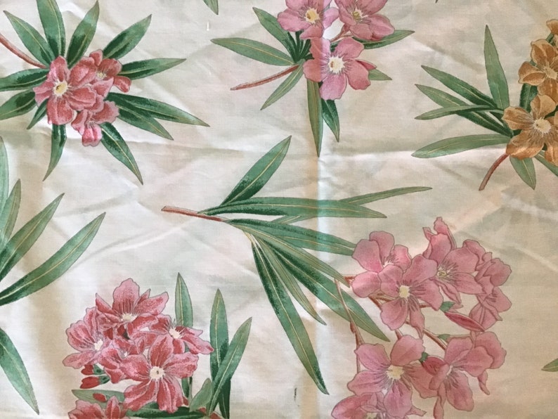 May include: White fabric with a floral pattern featuring pink flowers and green leaves.