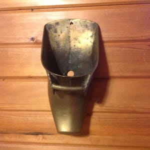 May include: A brass wall-mounted urinal, a vintage bathroom fixture.