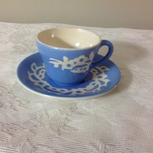 May include: A blue and white teacup and saucer set with a floral design. The cup and saucer are both decorated with a white floral pattern on a light blue background.