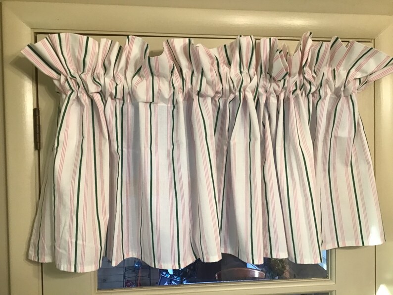 May include: White valance with pink and green stripes. The valance is gathered and has a ruffled edge.