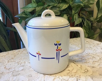 May include: White ceramic teapot with a blue and red floral design. The teapot has a lid and a handle.