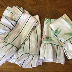 May include: Three pillowcases with green and pink stripes and a floral print. The pillowcases have a ruffled edge and are trimmed with green.