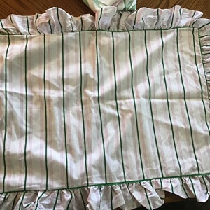 May include: White pillowcase with green and pink stripes and a ruffled edge.
