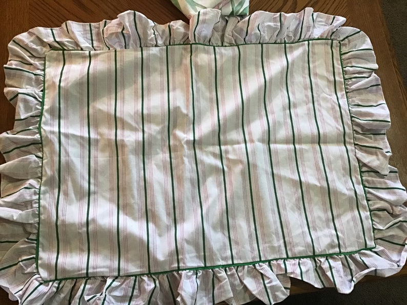 May include: White pillowcase with green and pink stripes and a ruffled edge.