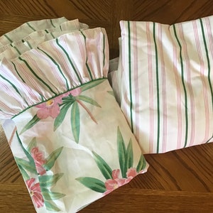 May include: Two white cotton pillowcases with green and pink stripes. One pillowcase has a ruffled edge and the other has a floral print with pink flowers and green leaves.