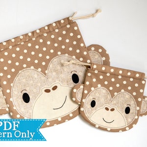 May include: Two brown fabric drawstring bags with a white polka dot pattern. The bags feature a brown and white monkey face with black eyes and a brown nose.