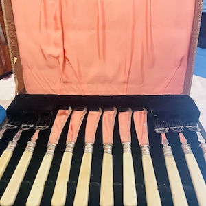 May include: A set of ten silver knives with ivory handles in a black velvet lined case.