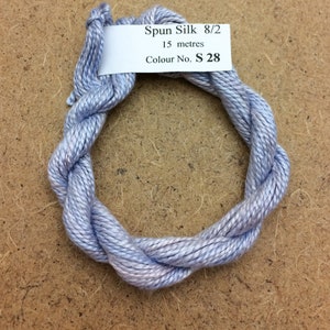 Puede incluir: Una madeja de hilo de seda hilada azul claro, etiquetada "Spun Silk 8/2, 15 metros, Colour No. S 28".