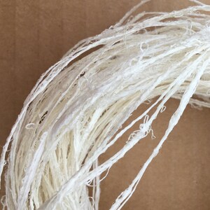 May include: A close-up of a white, natural fiber rope, made from paper, perfect for crafting and decorating.