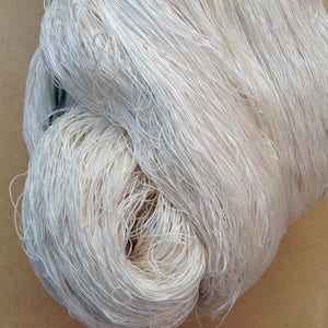 May include: A close-up of a bundle of white yarn, showing the individual strands of the yarn.