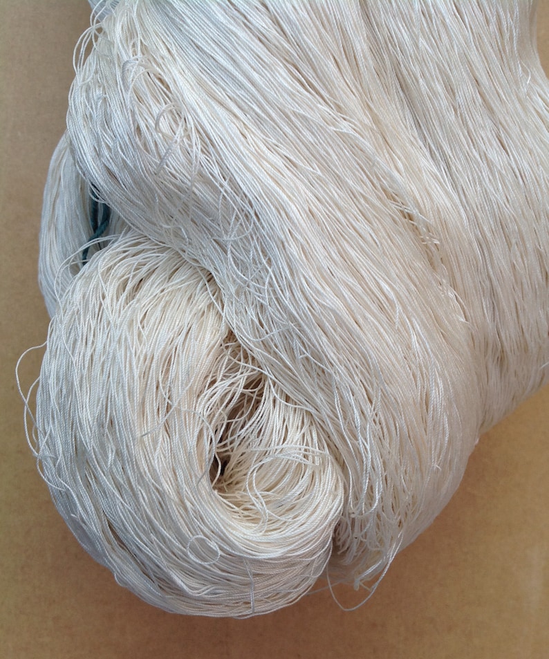 May include: A close-up of a bundle of white yarn, showing the individual strands of the yarn.