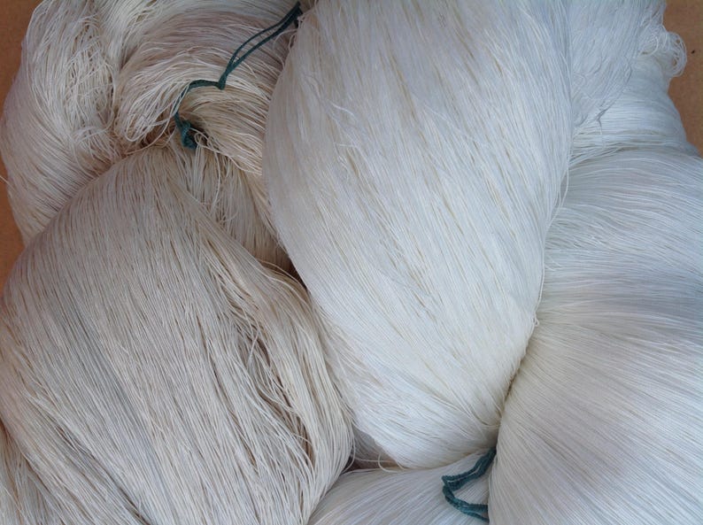 May include: A close-up of a pile of white yarn, with some green string visible.