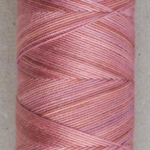 May include: A spool of pink and peach colored thread wound around a white cardboard tube.