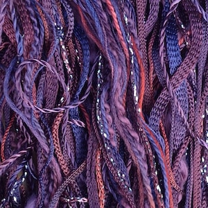 May include: A close-up of a bundle of purple, blue, and burgundy yarn with silver glitter thread woven throughout.