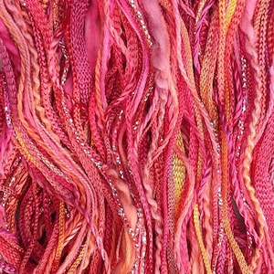 May include: A close-up of a bundle of colourful yarn with a mix of pink, orange, and silver threads.